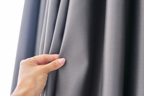 A woman inspecting grey blackout curtains